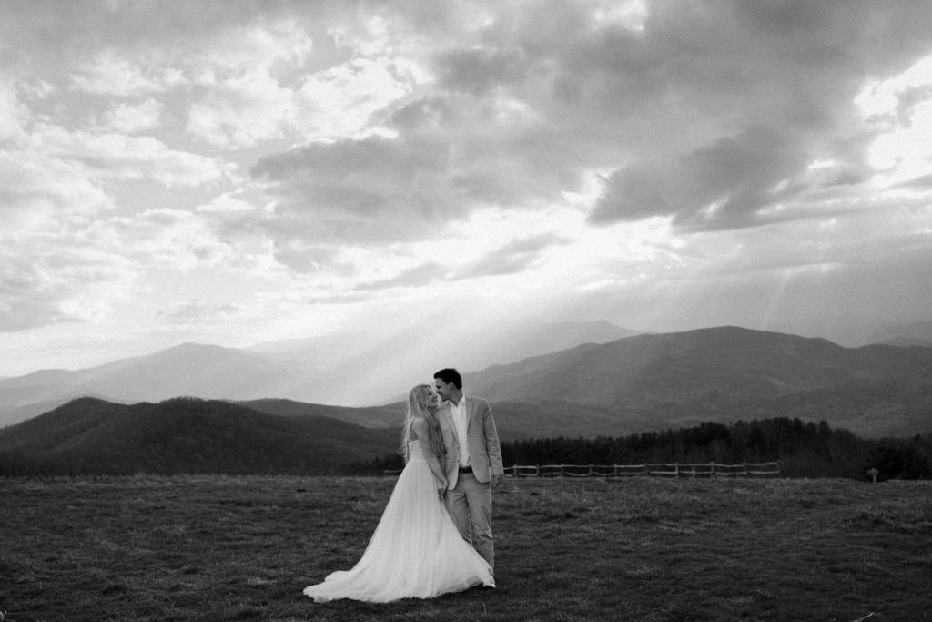 A man and a woman stand next to eachother and look at eachother in their wedding attire during their Asheville mountain elopement.