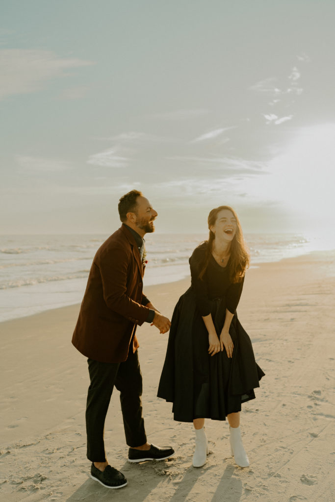A married couple laughs on the beach with the ocean behind them during their Hilton Head Beach Elopement