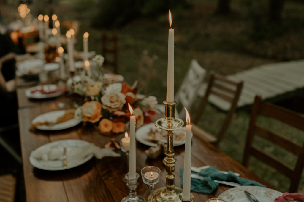 A beautiful wedding table, with flowers, candles, and mismatched chairs