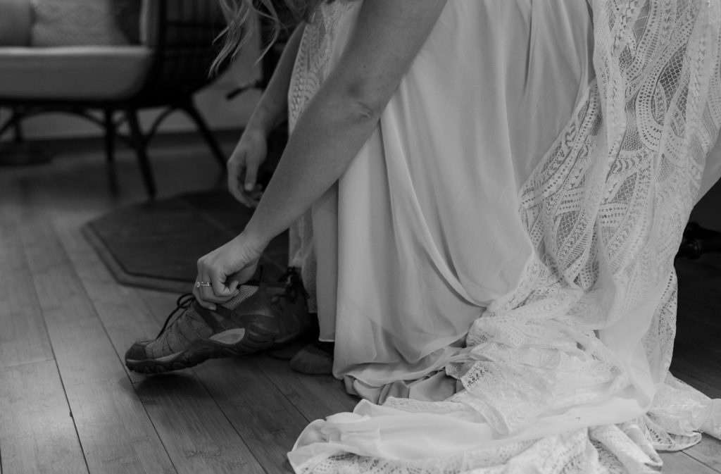 Bride putting on hiking shoes in a wedding dress
