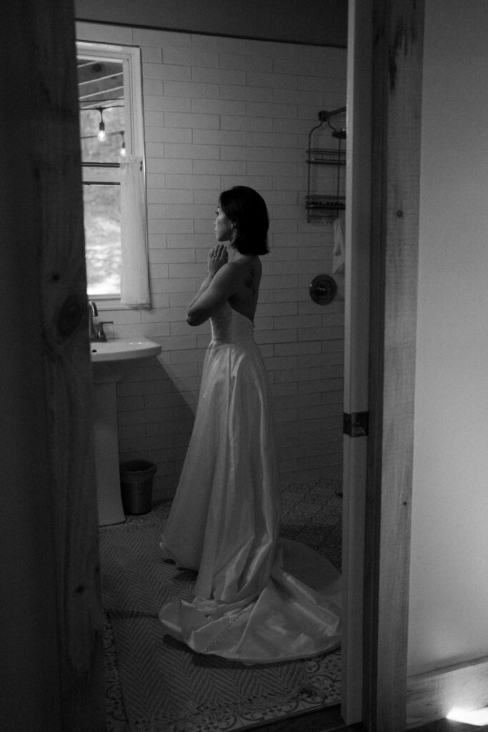 A girl standing in her wedding dress looking at herself in the mirror. 