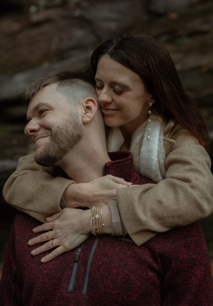 Close-up shot of a couple embracing, highlighting the woman’s accessories. Her earrings, bracelet, and layered scarf add stylish details to her outfit, complementing the cozy and well-coordinated look of the couple.