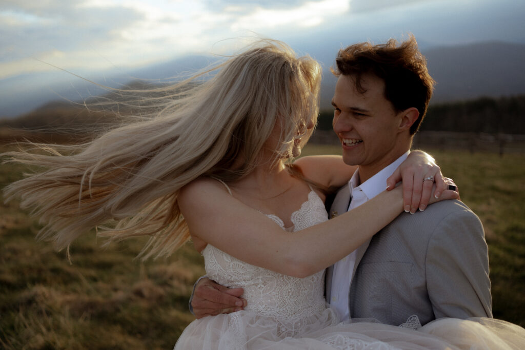 Groom lifts and twirls his bride with the Blue Ridge Mountains in the background, capturing the joy of their intimate wedding day.