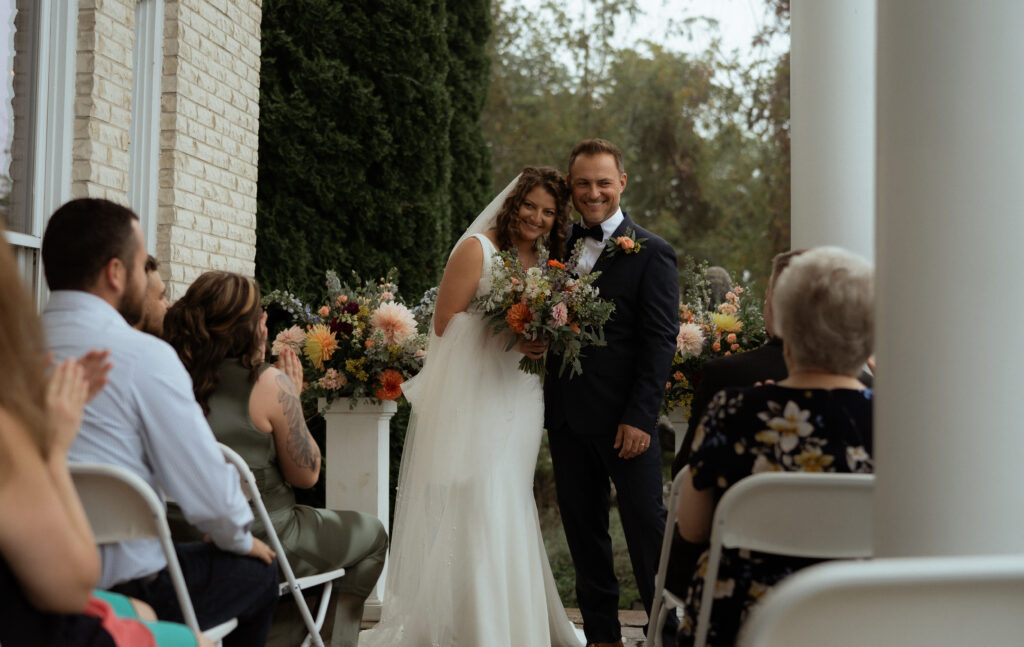 man and woman smile at their guests after exchanging their vows 
