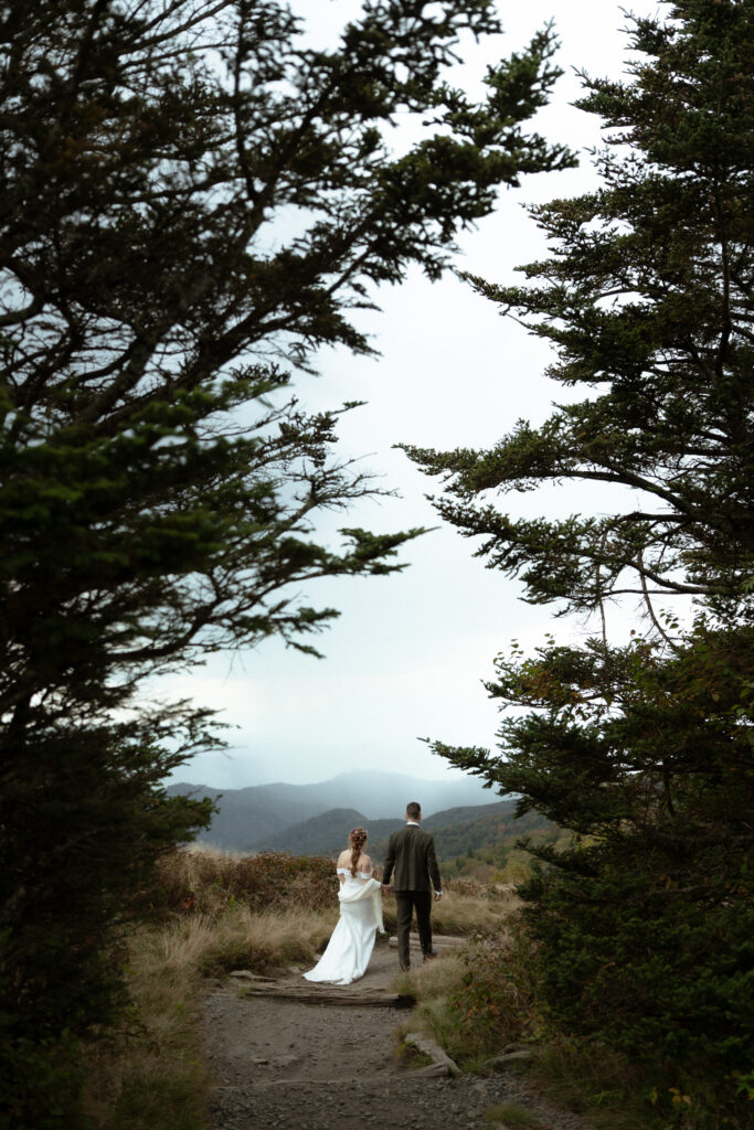 The bridge and groom walking through the alpine trees after the ceremony on Roan Mountain 