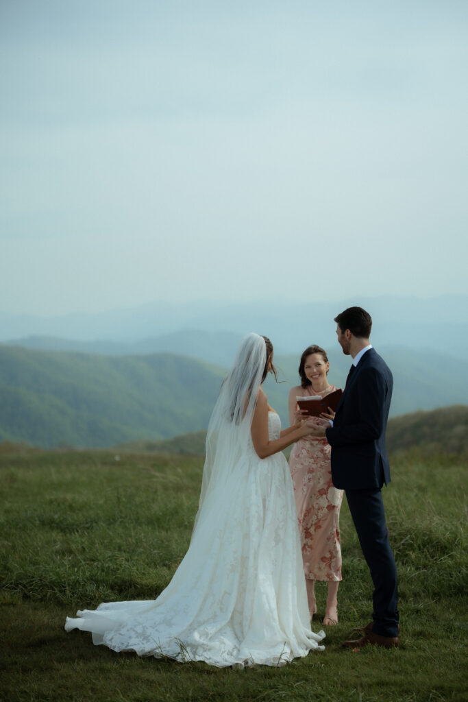 An officiant marrying a couple on top of Max Patch on a sunny day