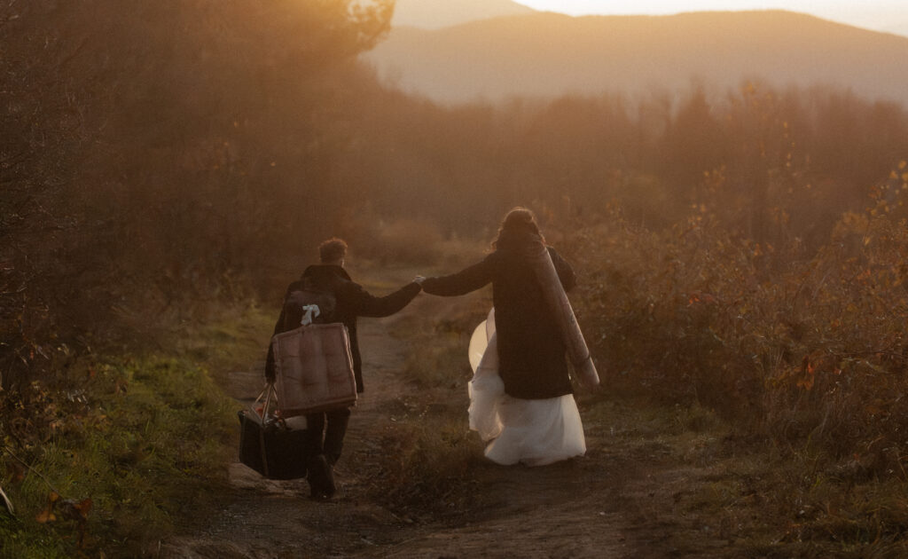 A married couple making their way down the mountain during sunset after getting married on top of a bald near the mountains of Asheville